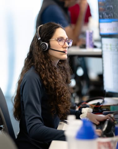 photo of stock trader sitting in front of a wall of monitors